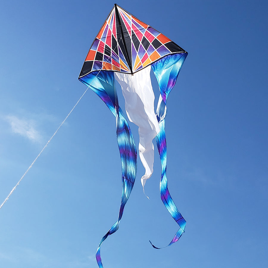 6.5 ft. Flo-Tail Delta Kite with gradient check design soaring high against a clear blue sky, featuring flowing 24-foot tails that catch the wind beautifully.