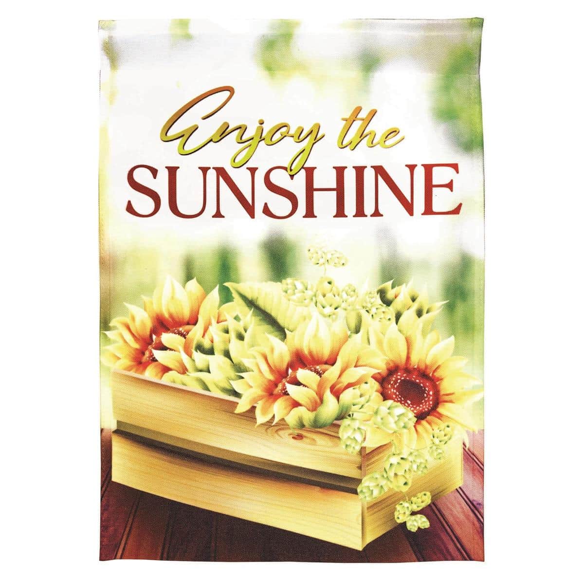 Bright Enjoy The Sunshine 13x18 garden flag showing a cheerful sun graphic and 'Welcome' text on printed polyester, displayed on a porch pole among potted plants.