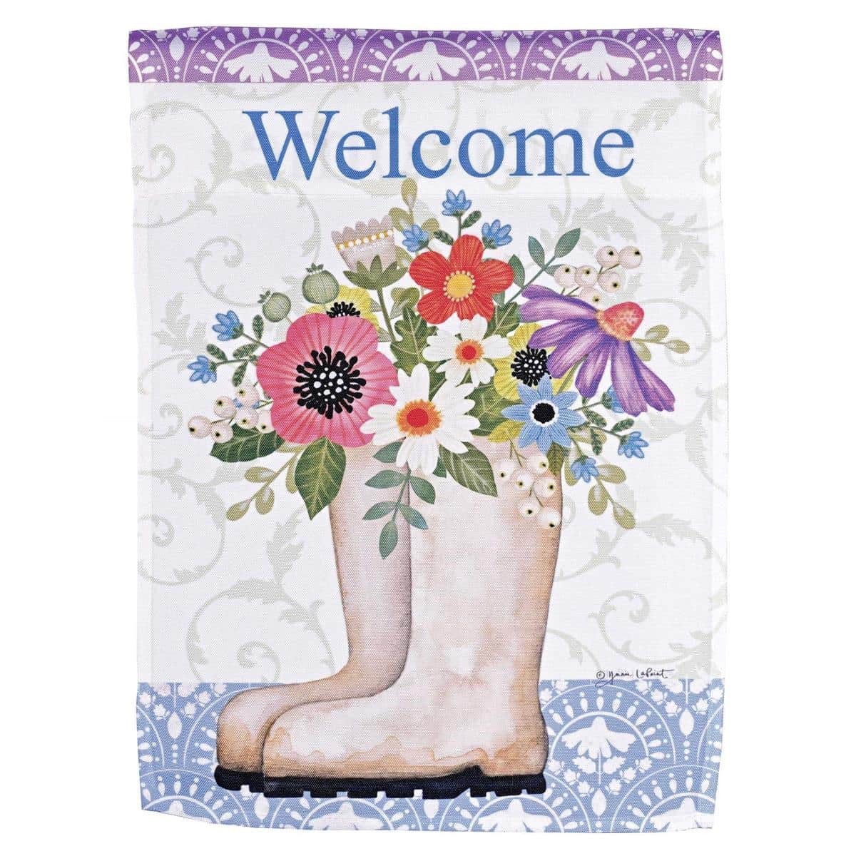 13x18 Floral Boots Welcome Garden Flag with printed boots overflowing with flowers and a clear Welcome message, shown mounted on a standard garden flag pole beside a porch planter.