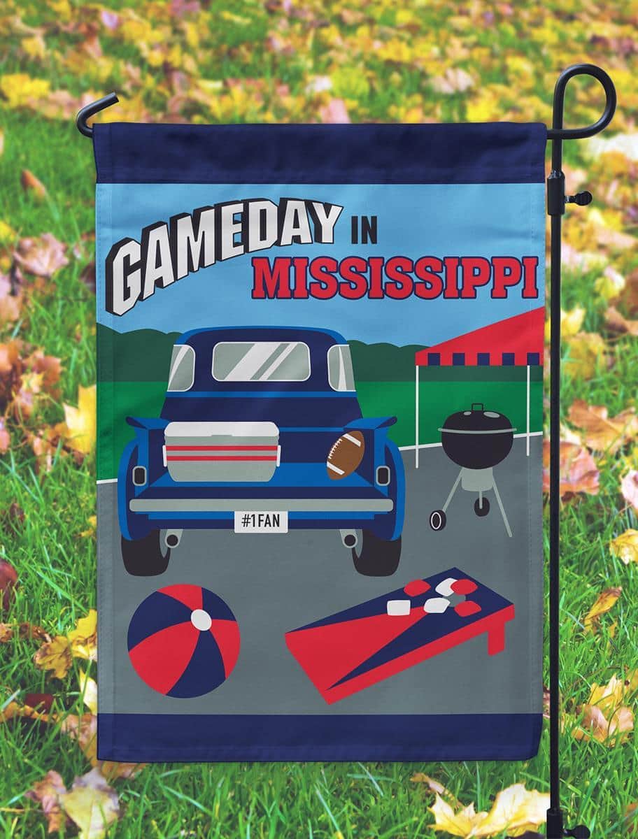 13x18 Gameday Mississippi garden flag in navy and red with double applique design shown mounted on a metal yard pole in a grassy front yard setting.