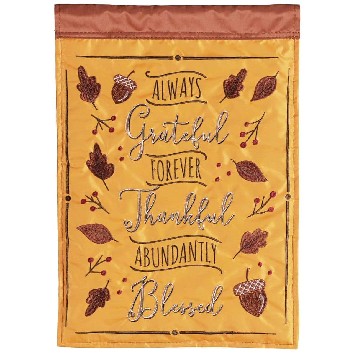 13x18 inch Grateful Thankful Blessed garden flag featuring double applique lettering and layered fabric accents displayed on a standard black metal garden flag pole in a flowerbed with seasonal blooms visible behind the flag.