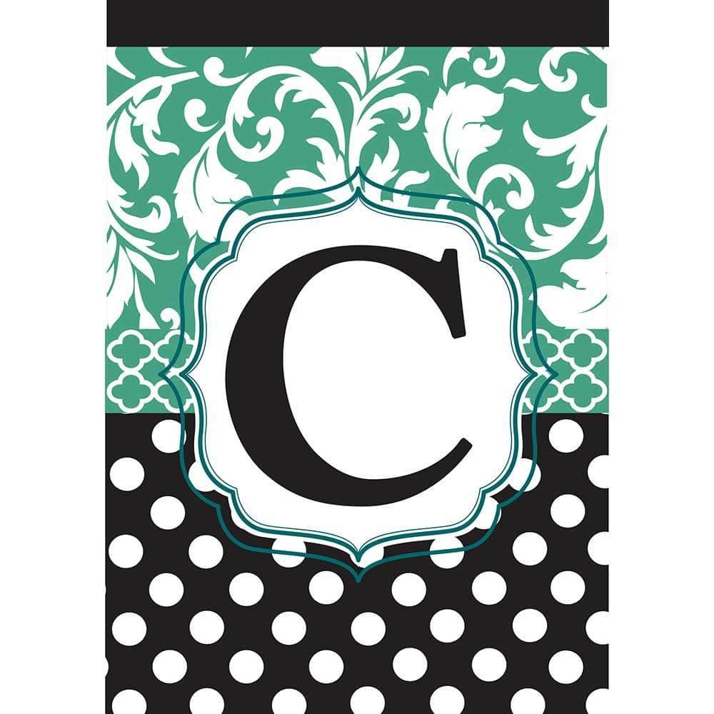 Close-up of a 13x18 garden flag featuring the letter C in elegant aqua script on a black background, mounted on a metal stand beside a porch entry.