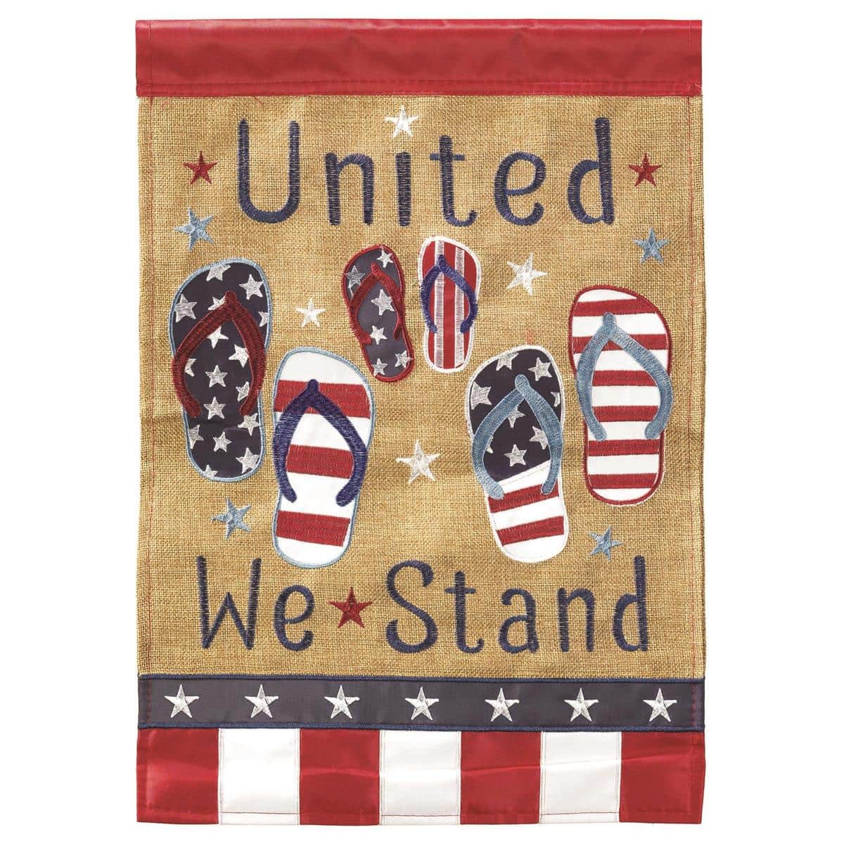Close-up photo of United We Stand Flip Flops 13x18 garden flag showing double applique stars and stripes flip flop motif in red white and blue hanging on a metal garden pole in a sunny yard.