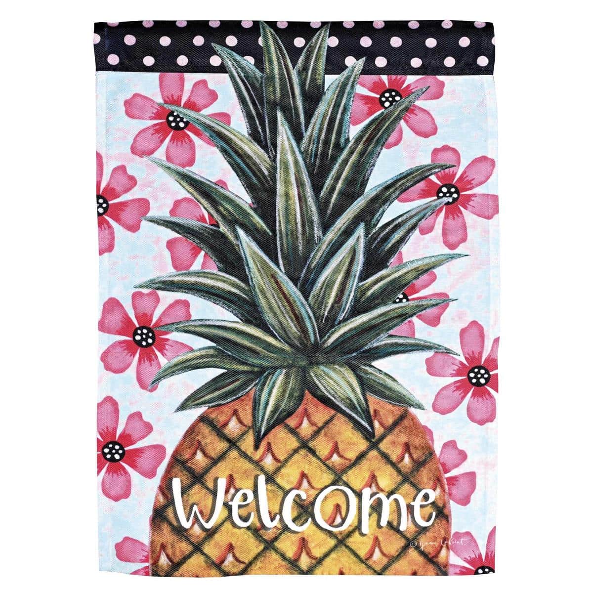 Printed Welcome Pineapple garden flag on a 13x18 inch fabric panel displayed on a black metal pole in a sunny front yard with green shrubs and potted flowers nearby.