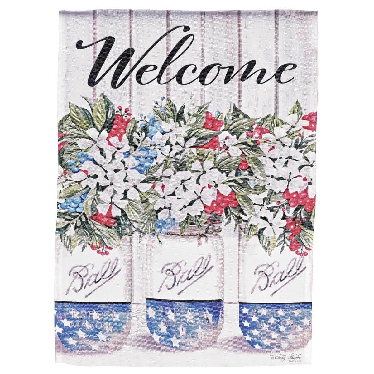 Photo of the Welcome Red White Blue Blooms 30x44 printed banner flag hanging from a porch post, showing vivid red white and blue floral motifs and a large clear "Welcome" message.