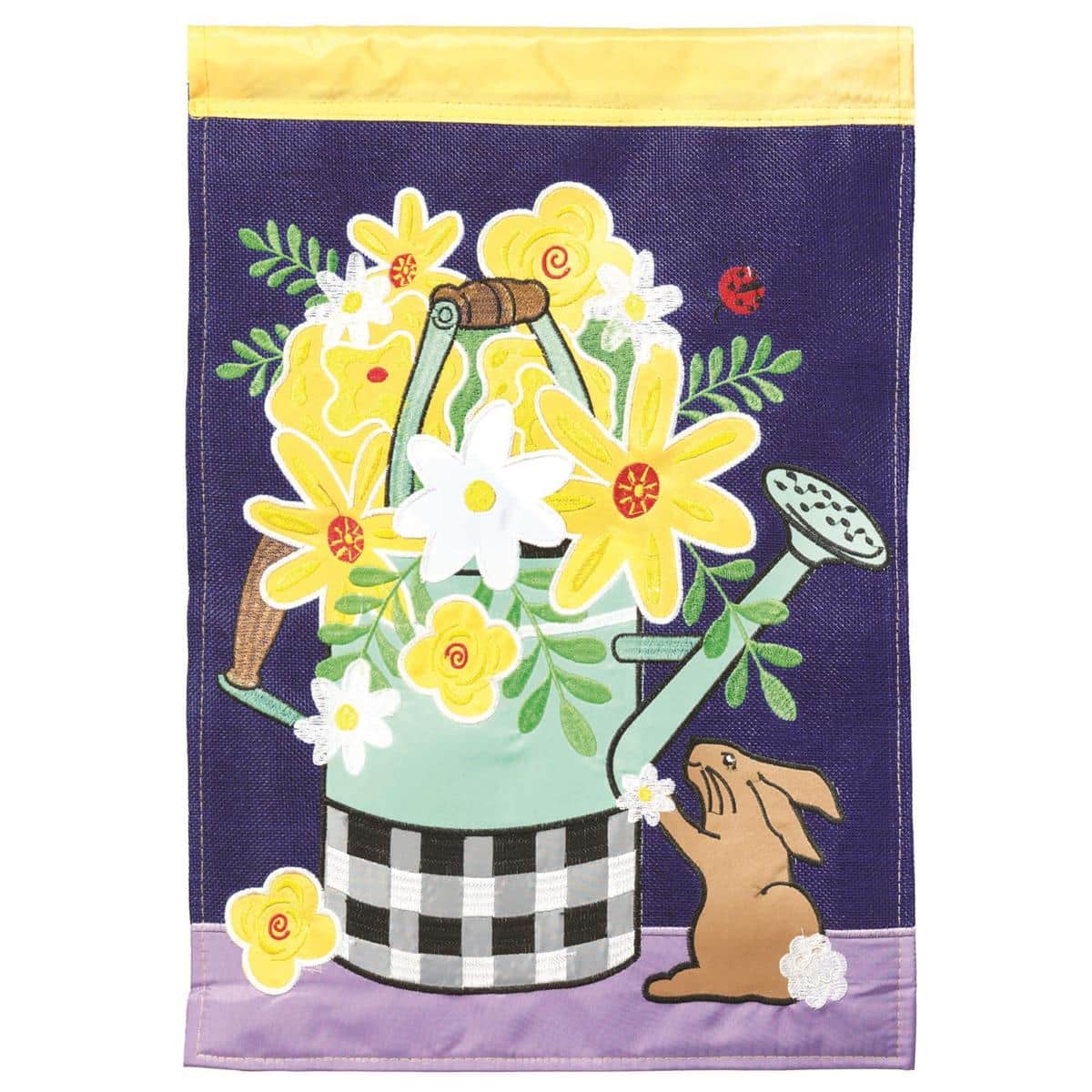 13x18 yellow flowers watering can double applique garden flag on metal pole in a sunny garden bed with green foliage and stone pathway in the background.