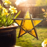 Amber 5-Point Star Hanging Tealight Lantern featuring textured glass and metal accents hanging in a bright indoor space.