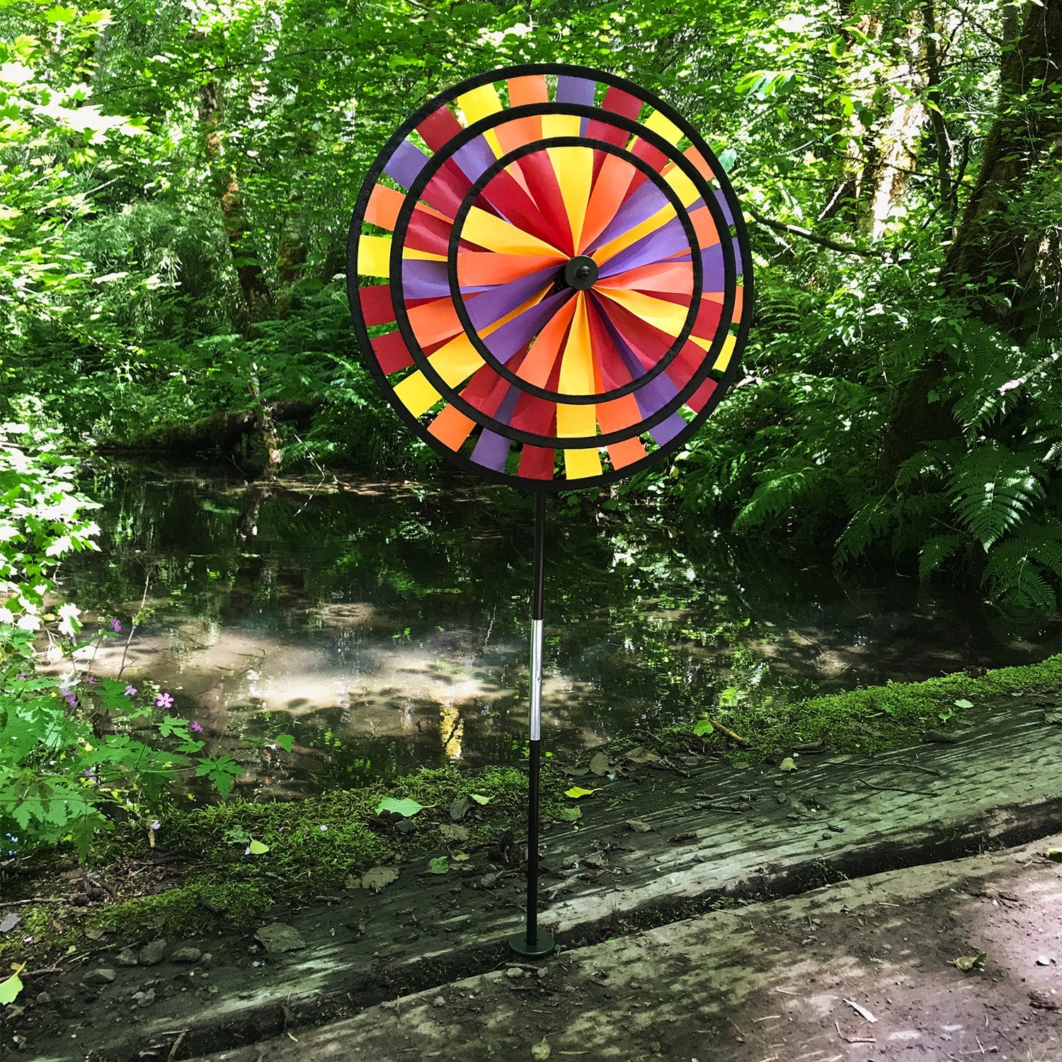 Vibrant Autumn Triple Wheel Spinner featuring three colorful wheels dancing in the wind, showcasing fall hues of red, orange, and yellow in a garden setting.