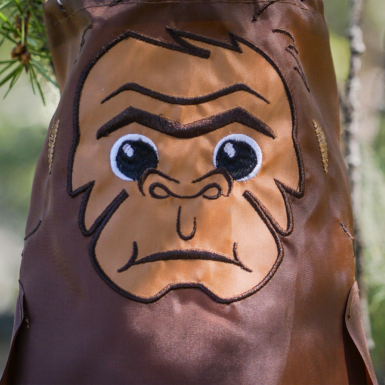 Baby Bigfoot 30" Breeze Buddy windsock featuring adorable applique and embroidery details, swaying gracefully in a garden setting.