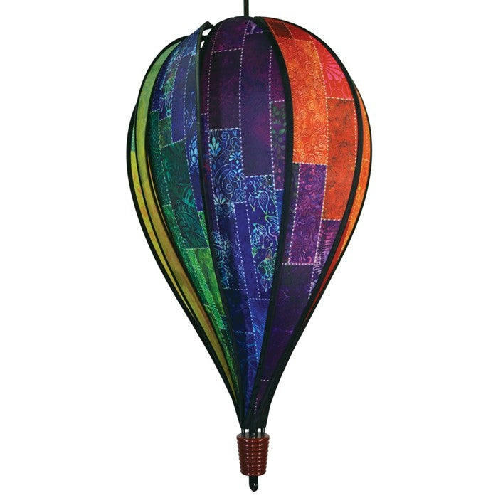Batik Quilt 10-Panel Hot Air Balloon Spinner in rainbow colors, spinning gently in a garden setting, showcasing intricate batik designs.