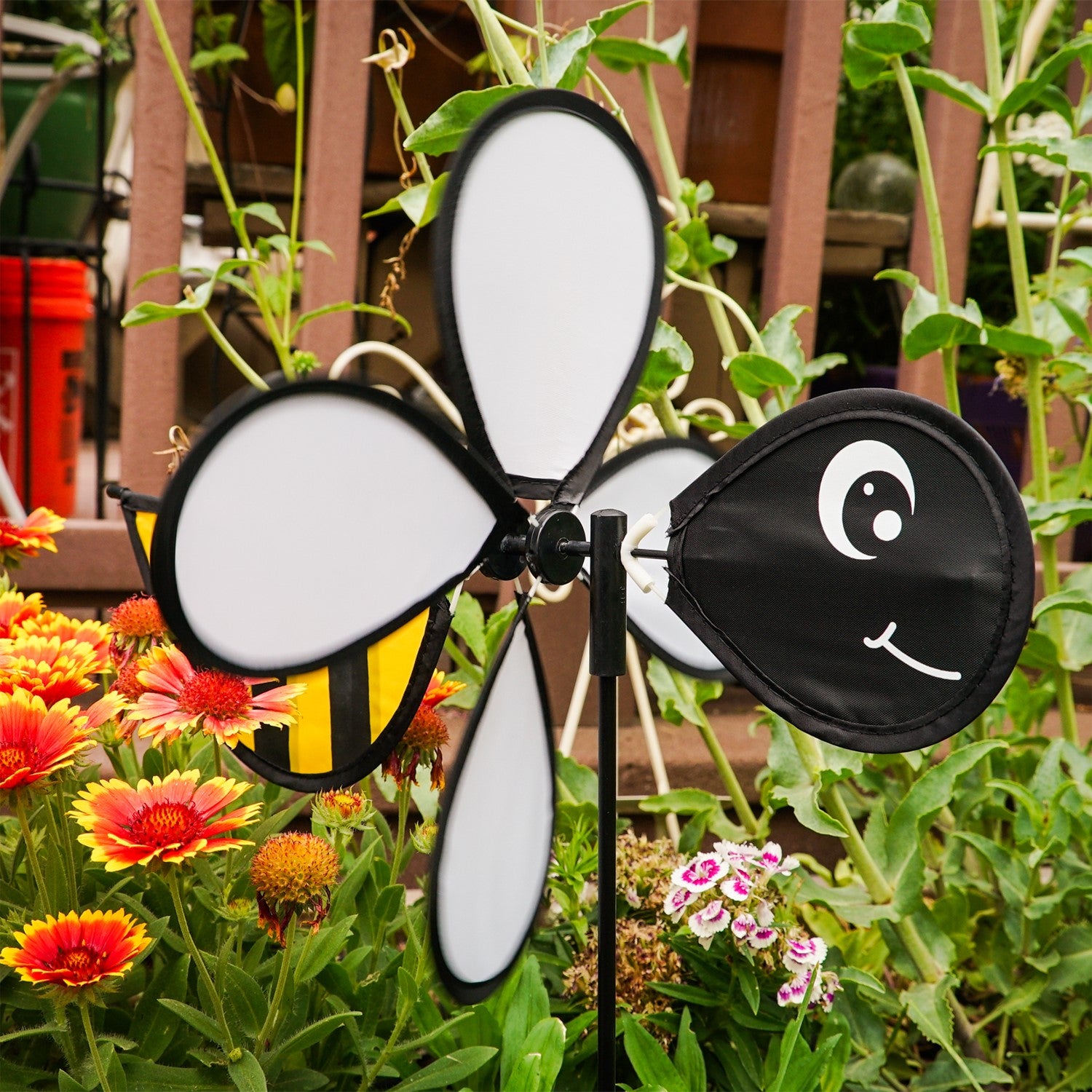Bee Baby Spinner with colorful 12-inch wheel and bee design, elegantly spinning in a sunny garden setting on a fiberglass pole.