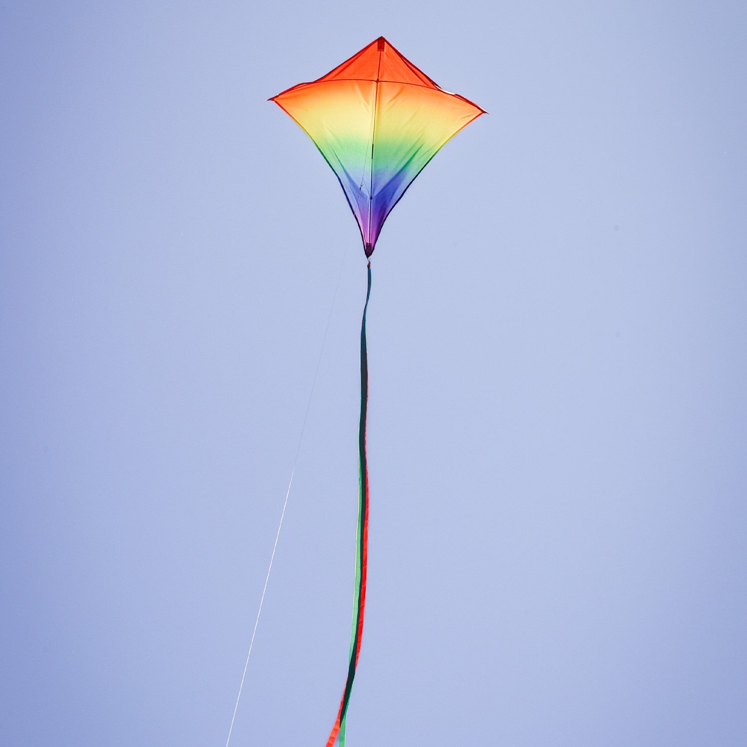 Blended Rainbow 30-inch diamond kite showcasing vibrant colors with flowing tails, soaring against a blue sky during a sunny day.