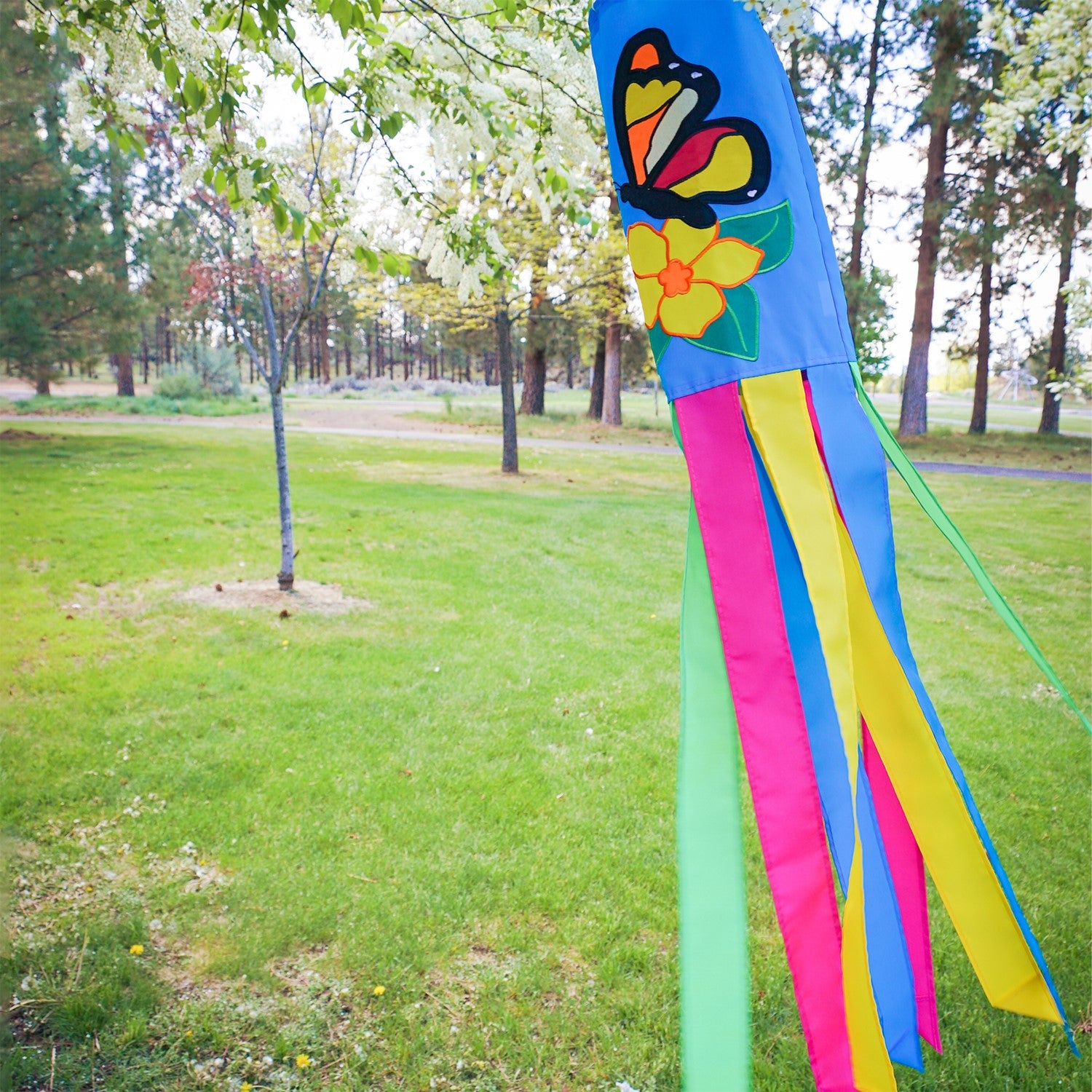Butterfly 40-inch windsock with bright colors and detailed applique graphics hanging outdoors, fluttering in the breeze against a sunny backdrop.