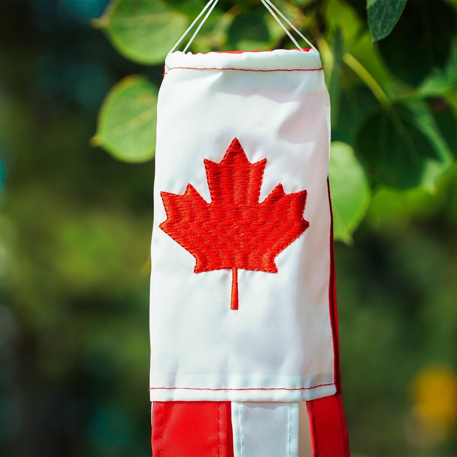 Canada 18-inch windsock displaying a bright maple leaf design, fluttering in the breeze outdoors with six colorful tails.
