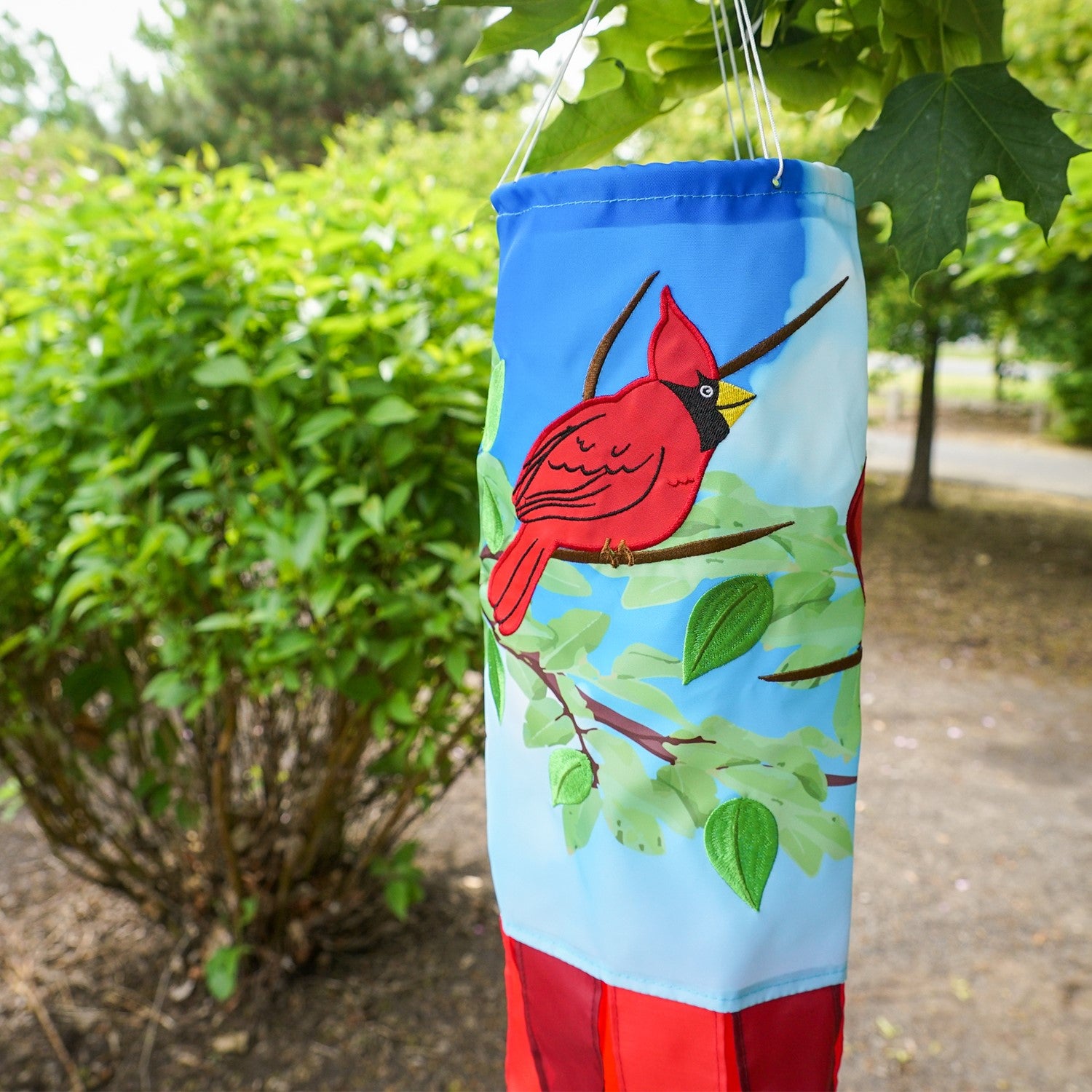 Cardinal 40" Inspiration Windsock with vibrant detail, featuring a red cardinal design and color-coordinated tails, hung as an outdoor decoration.