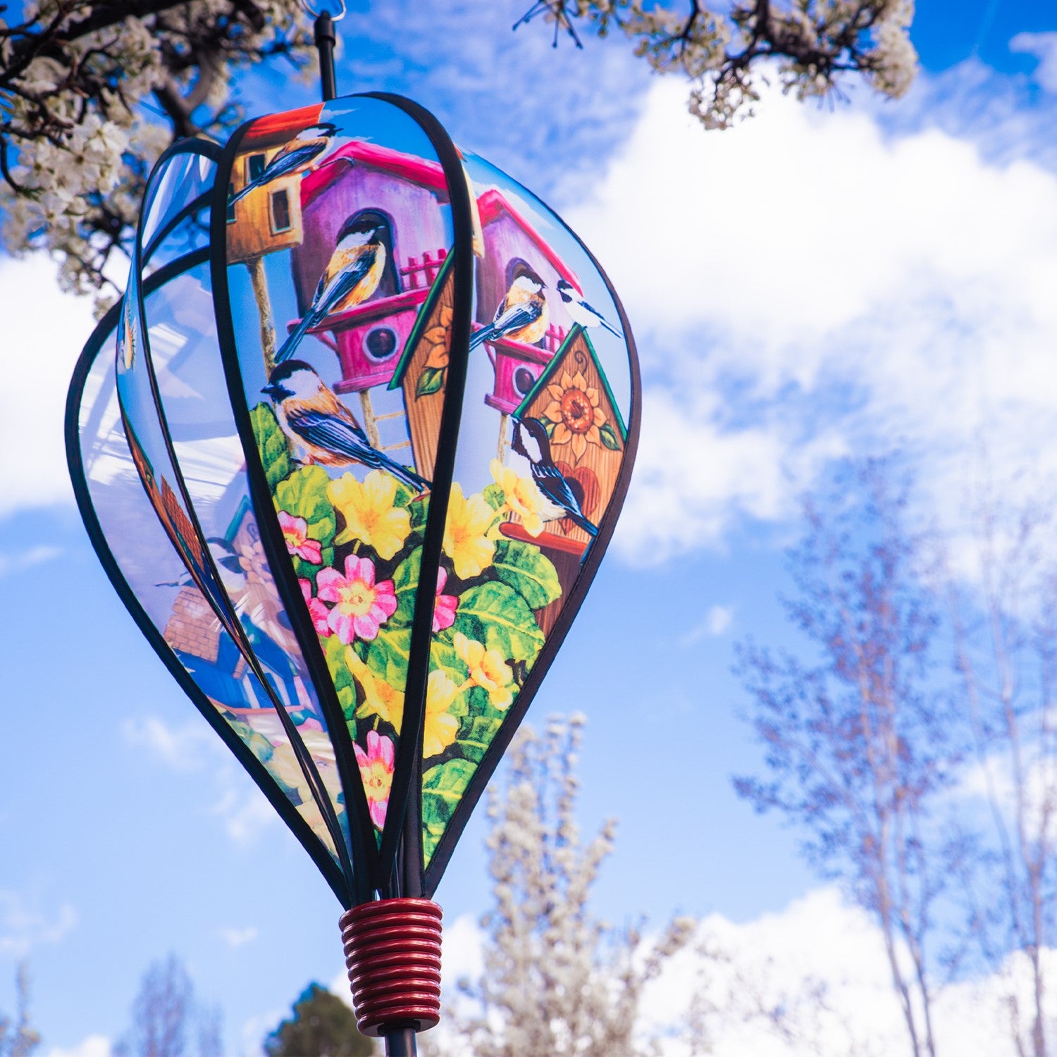 Chickadee Birdhouse Hot Air Balloon spinning in the breeze, showcasing vibrant chickadee graphics and a colorful curlie tail adorned from a wooden basket.
