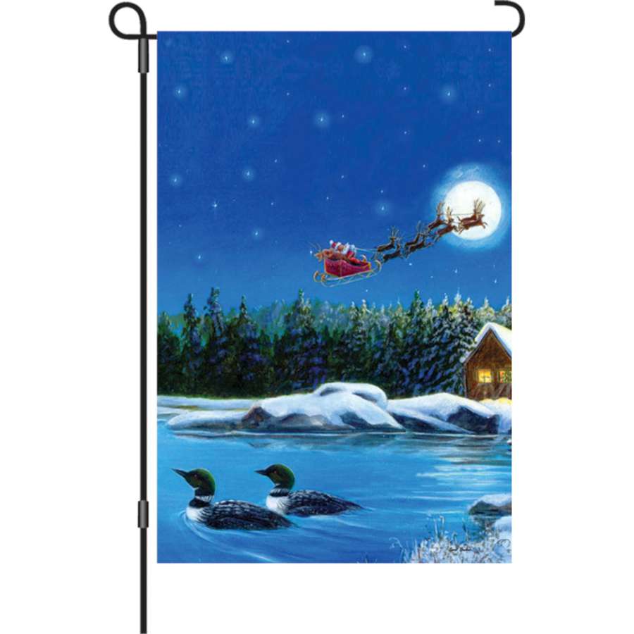 Illuminated 12 in. Christmas Loons flag showcasing vibrant winter colors and festive loons design, displayed in a garden setting at nighttime.