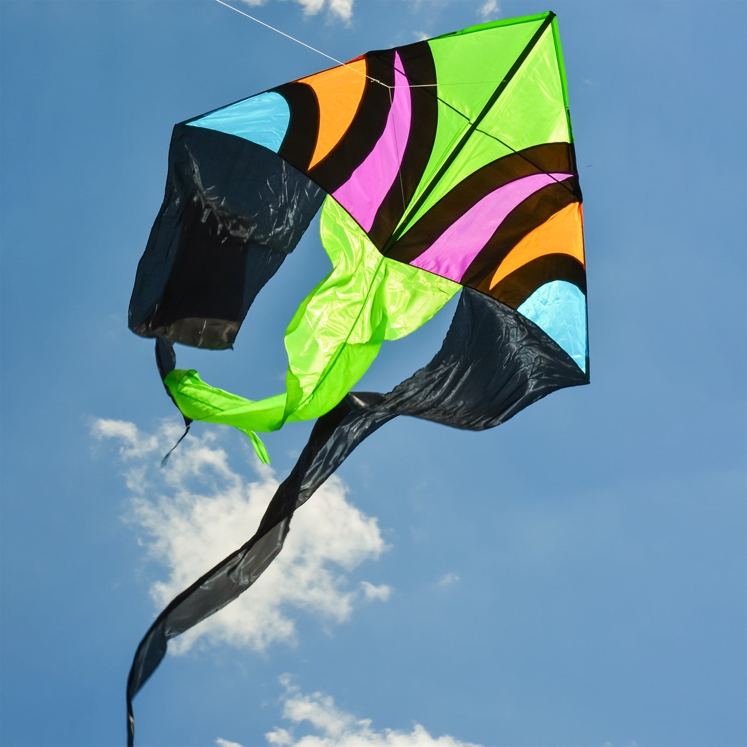 Dashiki 77' Wave Delta Kite soaring against a blue sky, showcasing vibrant patterns and colorful tails, designed for outdoor enjoyment.