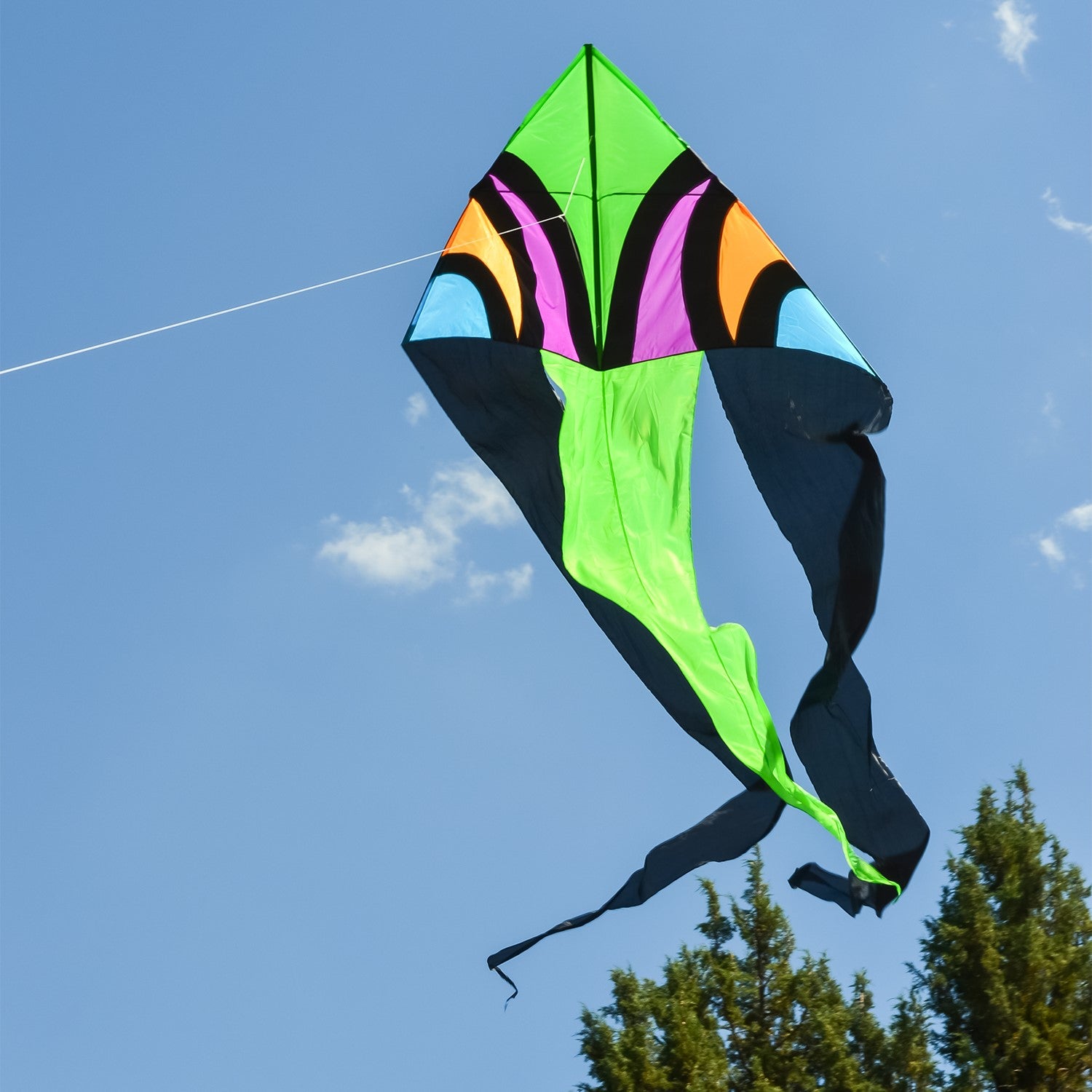 Dashiki 77' Wave Delta Kite soaring against a blue sky, showcasing vibrant patterns and colorful tails, designed for outdoor enjoyment.