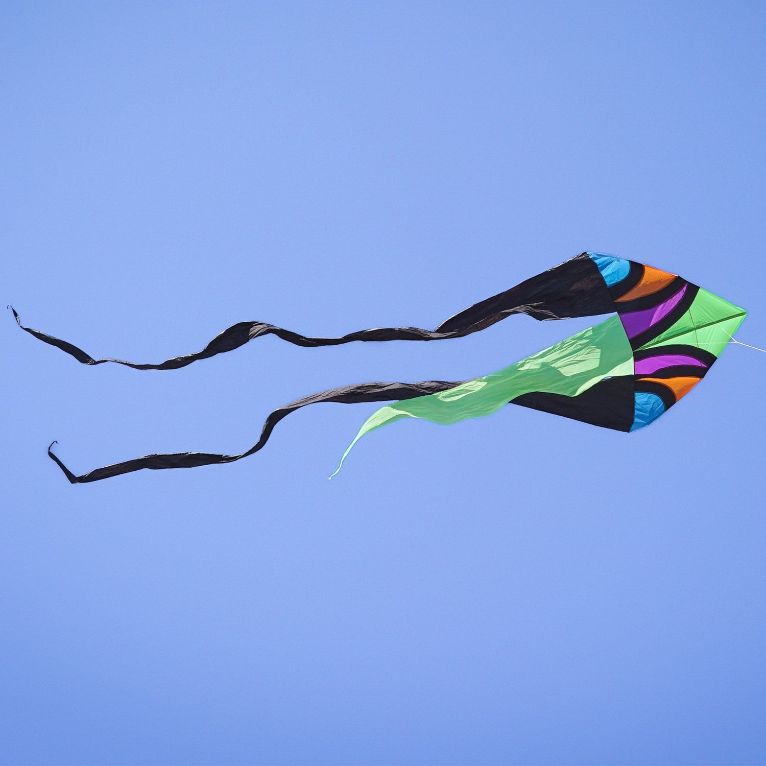 Dashiki 77' Wave Delta Kite soaring against a blue sky, showcasing vibrant patterns and colorful tails, designed for outdoor enjoyment.