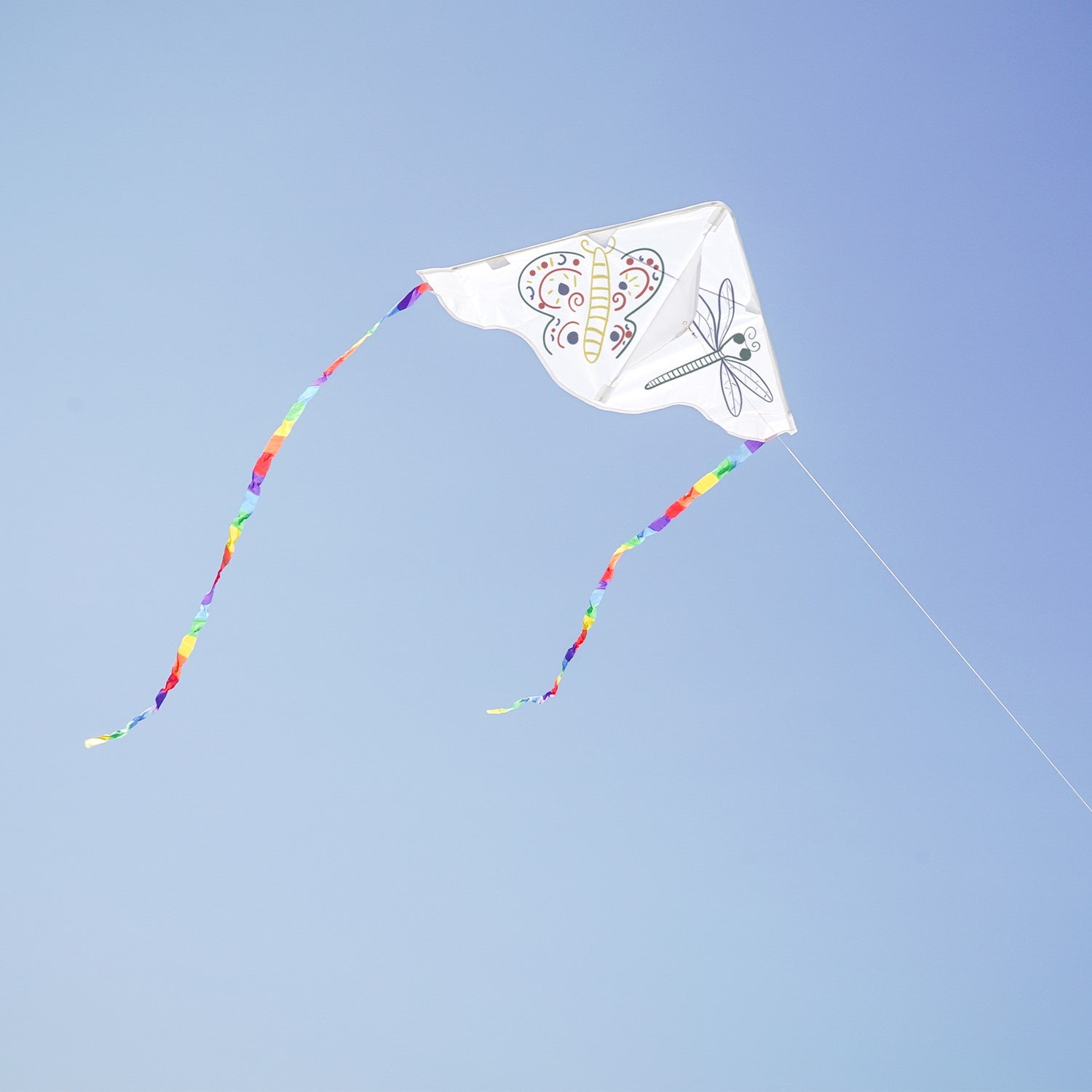 Visualize the Delta Coloring Kite: a 30-inch blank kite ready for artistic expression, showcasing its round edges and colorful rainbow stripe tails against a bright sky.