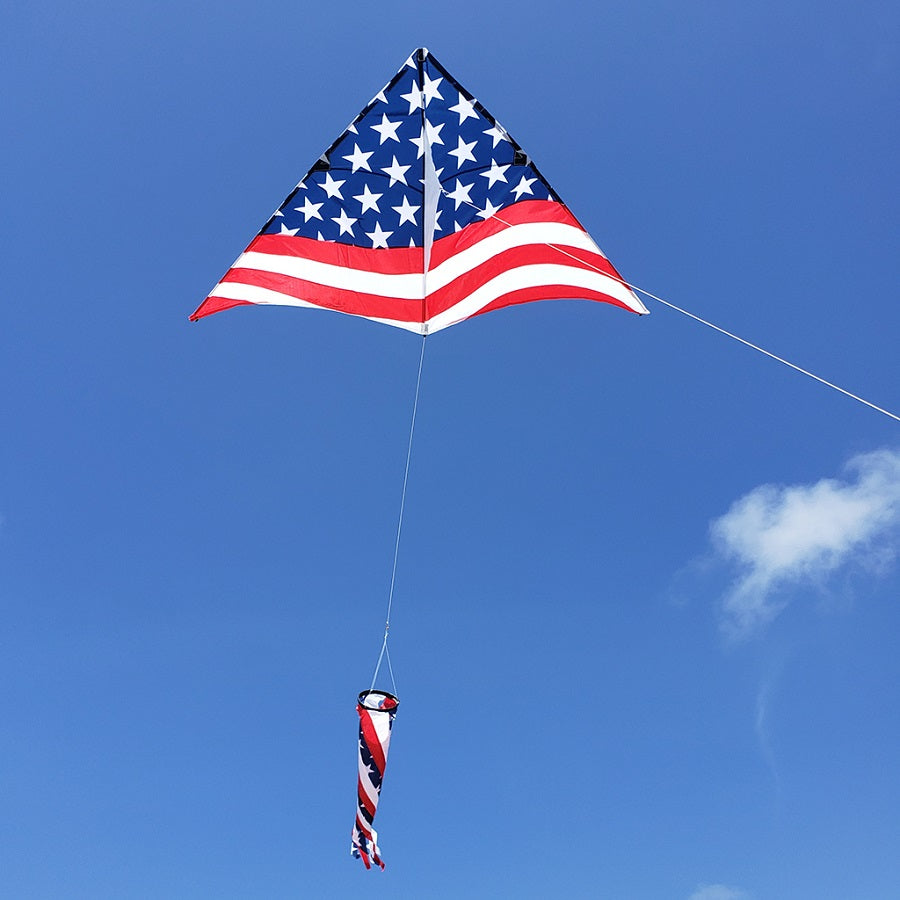 A 6.5 ft. Delta Kite - Old Glory Pack flying high in a clear blue sky, showcasing its vibrant colors and stable design.