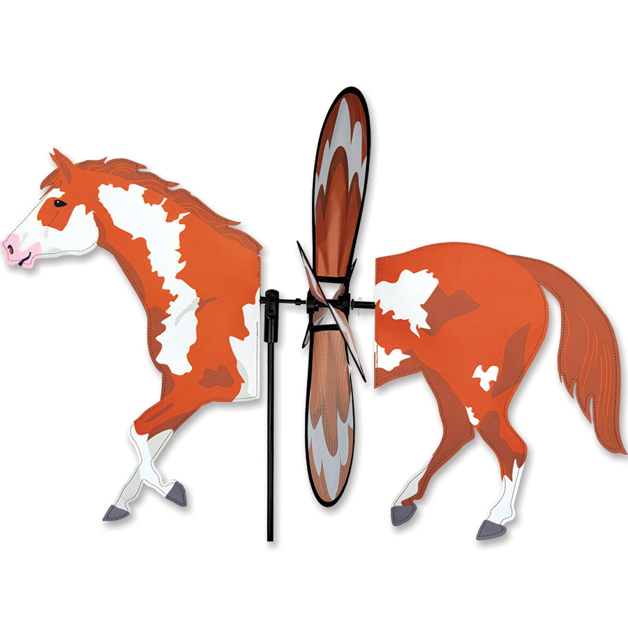 Deluxe Petite Spinner in Painted Horse design with colorful detailing, elegantly spinning in a garden setting against a blue sky.