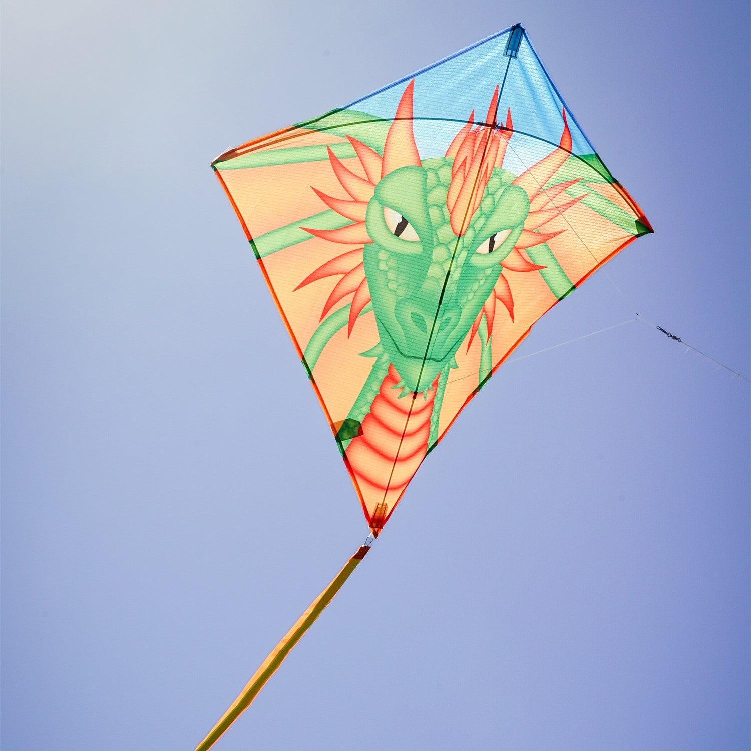Dragon 30 inch diamond kite with colorful dragon design soaring in clear blue sky, featuring three long tails for stability.