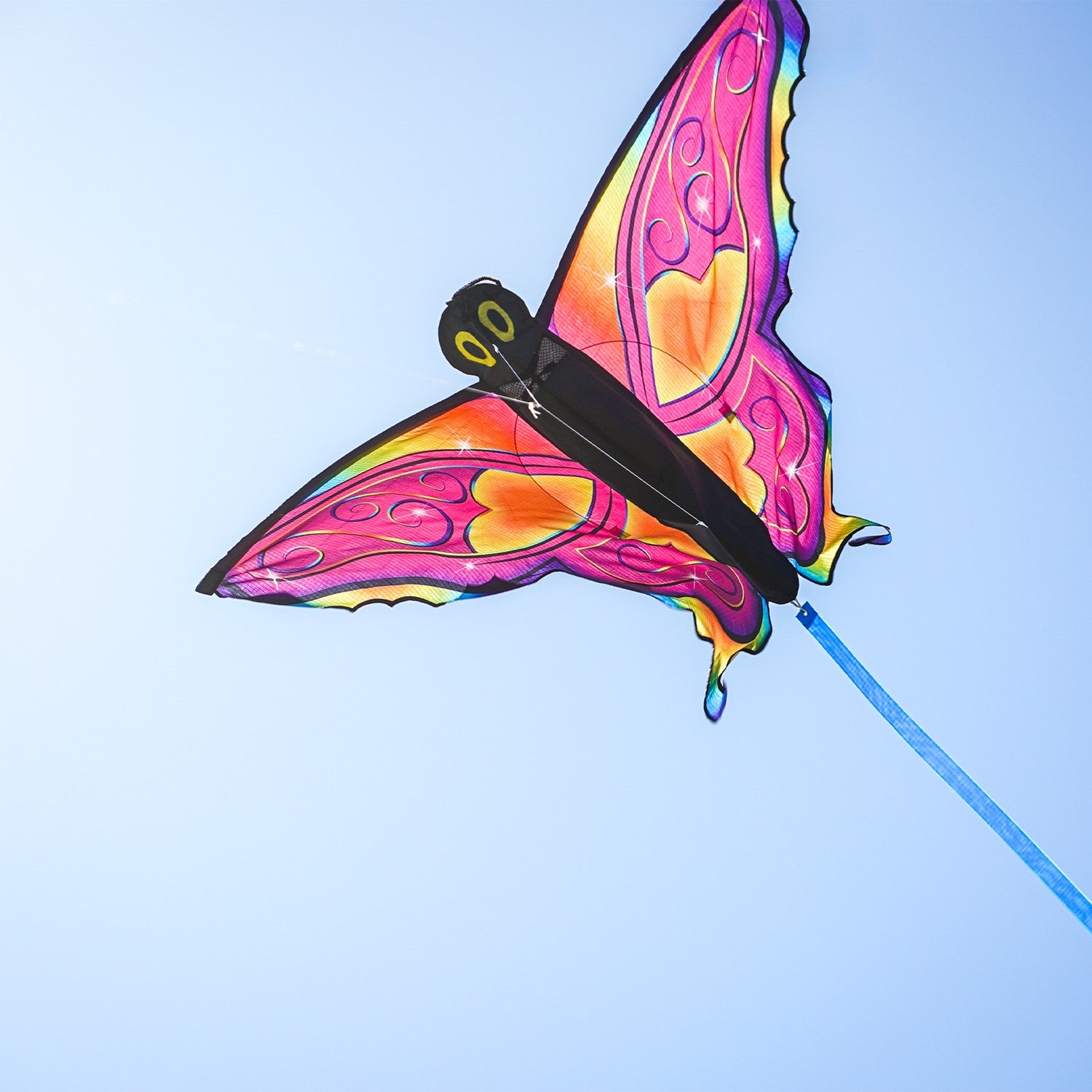 Brightly colored Fancy Butterfly Kite soaring in the sky, showcasing its vivid butterfly design and flowing tails during a sunny day.