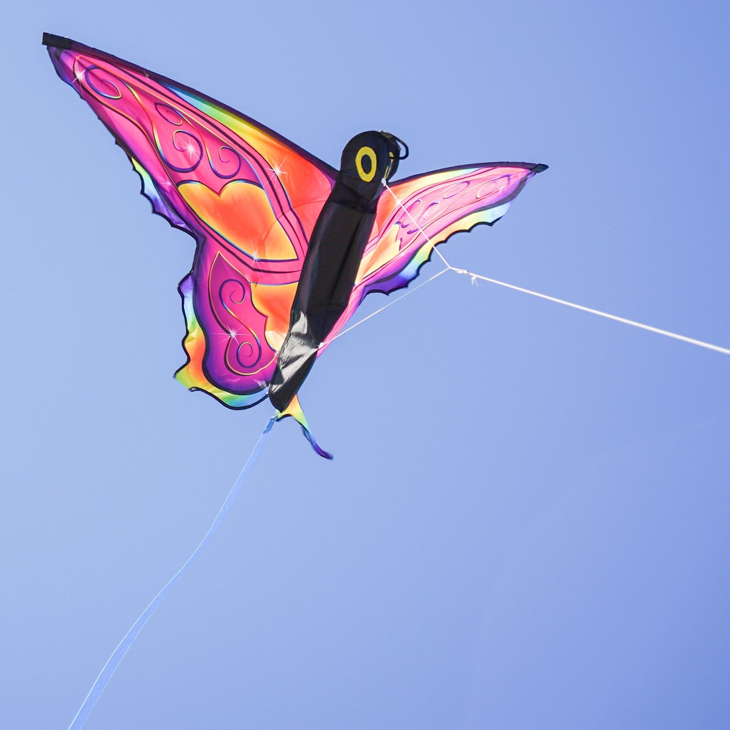 Brightly colored Fancy Butterfly Kite soaring in the sky, showcasing its vivid butterfly design and flowing tails during a sunny day.