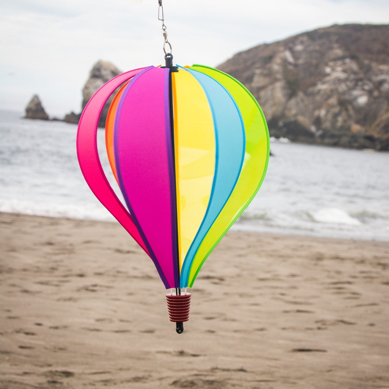 Colorful Fiesta 6-Panel Fabric Hot Air Balloon Spinner in a garden setting, highlighting its vibrant colors and balloon shape for outdoor decor.