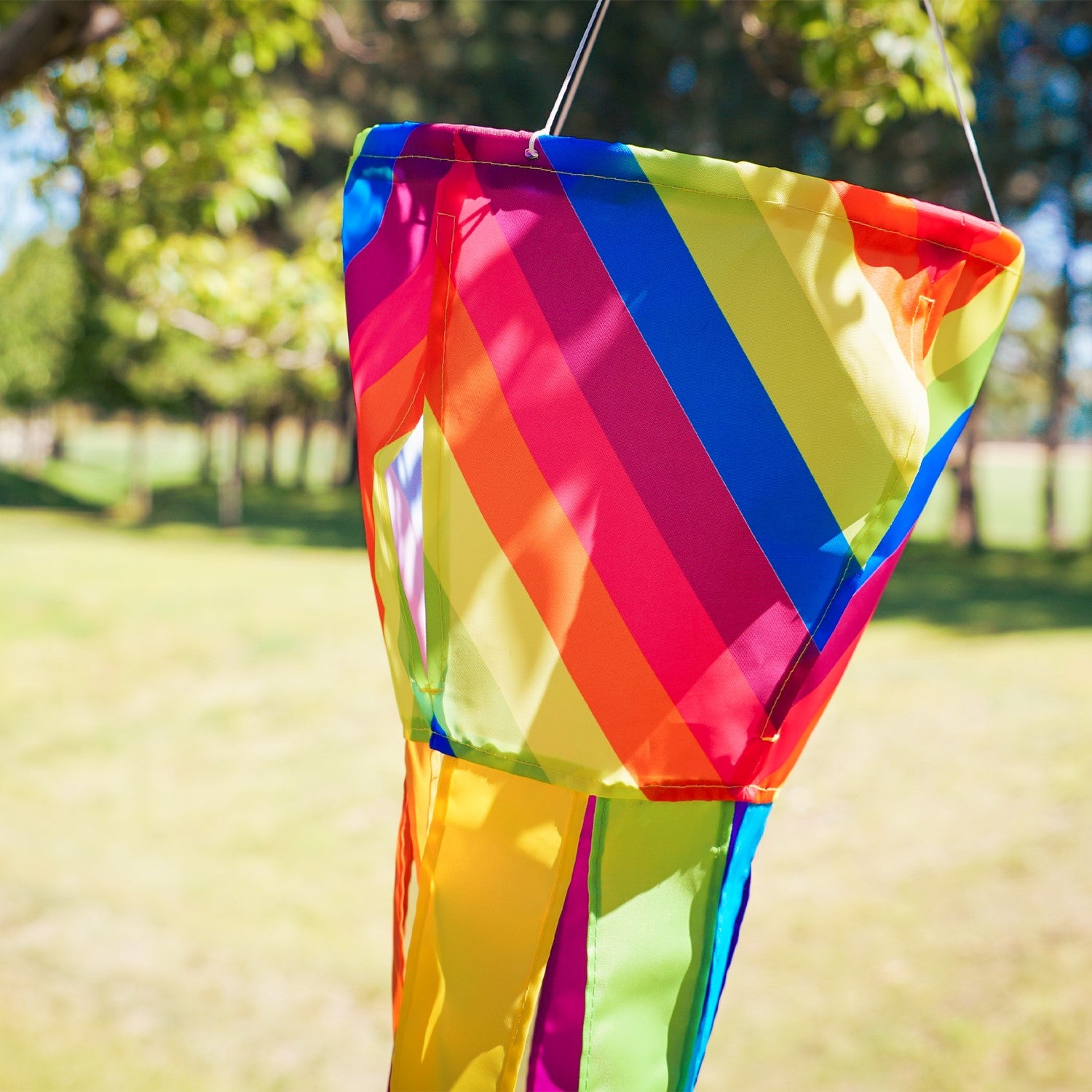 Colorful Fiesta Stripe Spinning Windsock featuring rainbow design with fluttering tails displayed outdoors, capturing motion in the breeze.