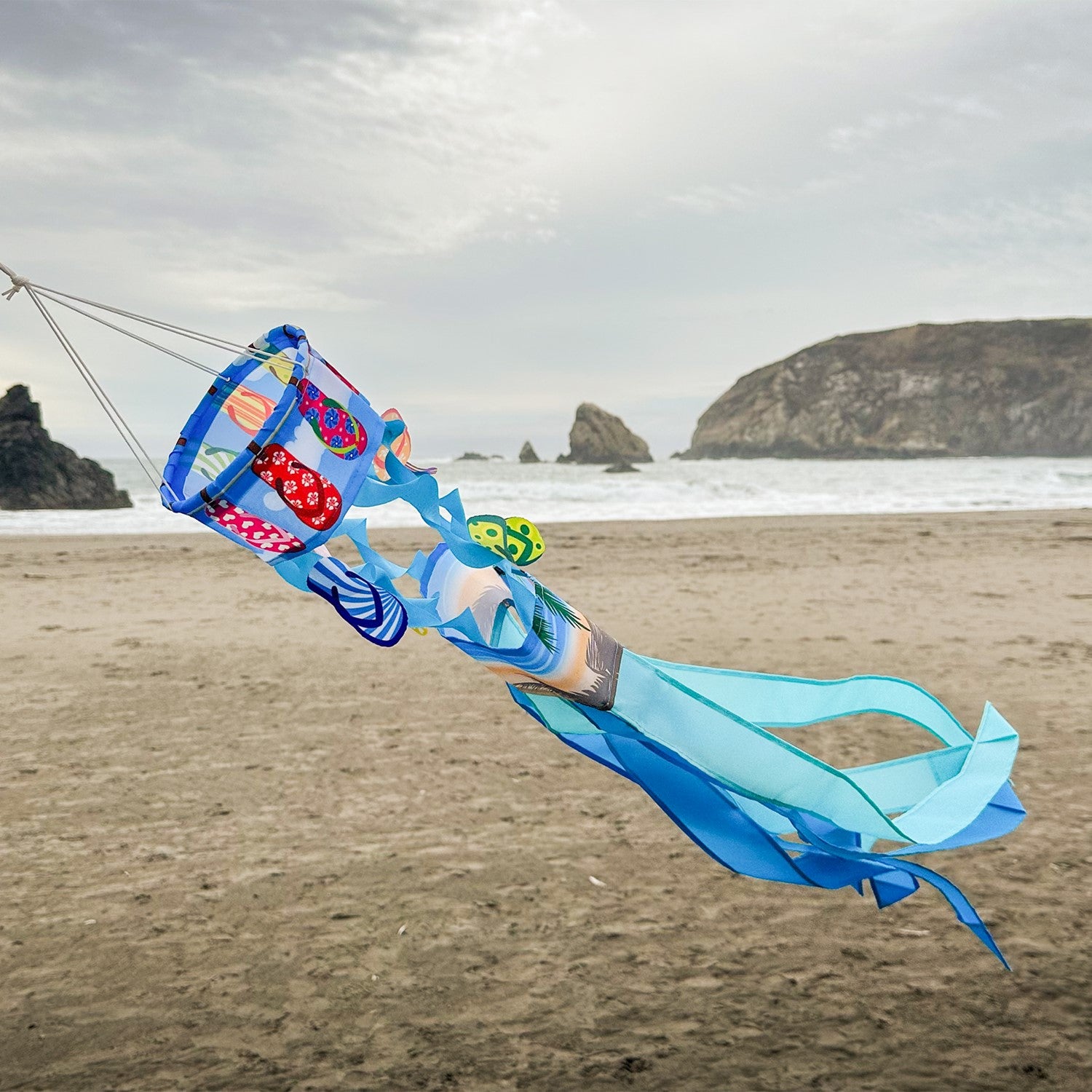 Flip Flops Twistair windsock with eight colorful tails displayed in a sunny garden, featuring whimsical curls that dance in the breeze.