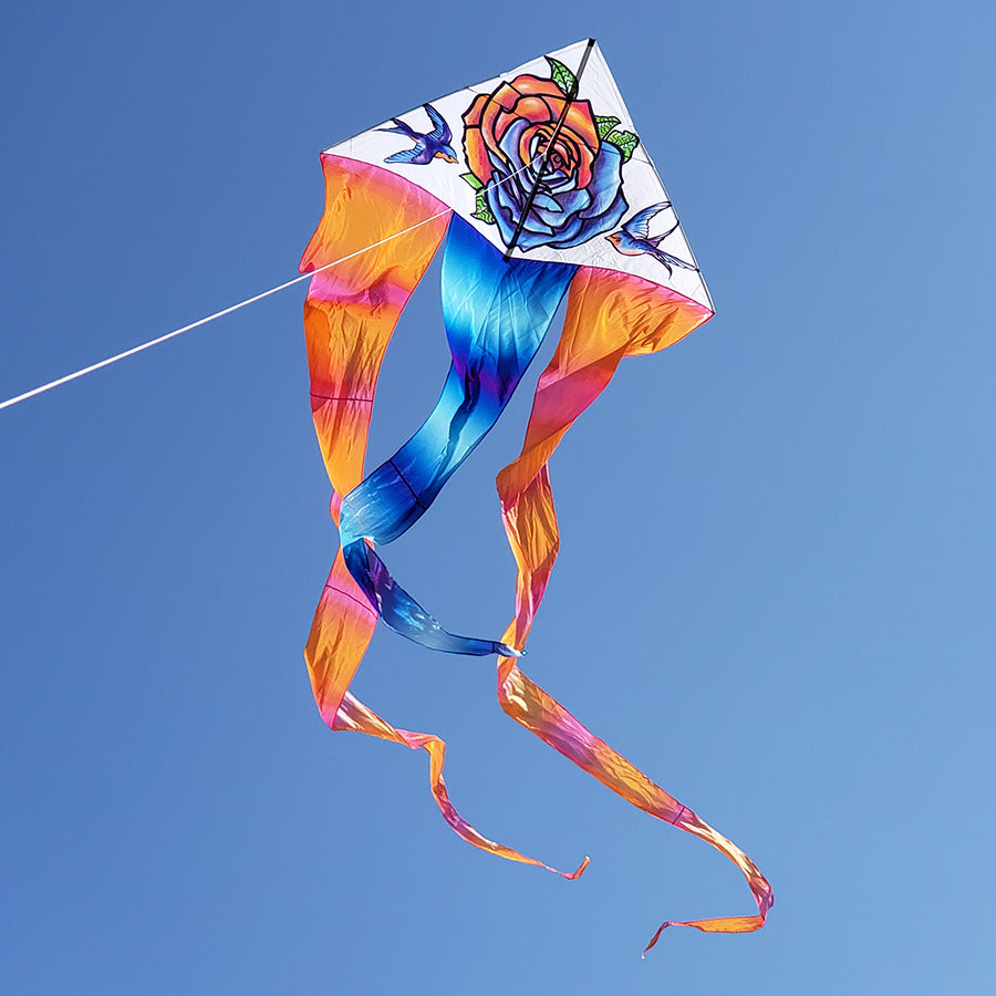 6.5 ft. Flo-Tail Delta Kite - Tattoo flying in clear blue skies, captivating viewers with its vibrant design and long flowing tails.