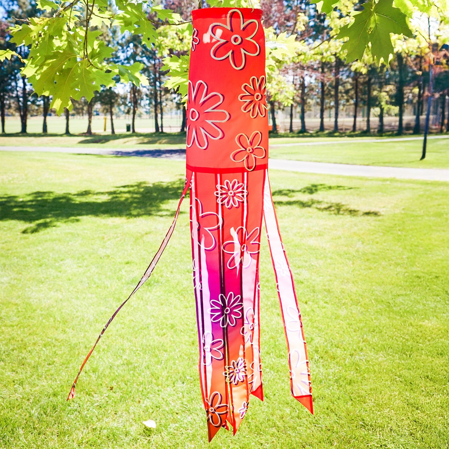 Flower Power 40-inch illusion windsock featuring vibrant flower designs and flowing tails, displayed hanging in a garden setting.