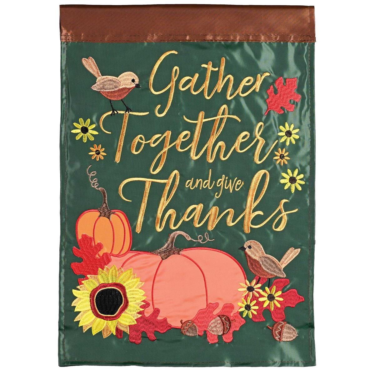 Gather Together-Give Thanks garden flag featuring colorful fabric appliques and embroidery, displayed outdoors on a pole in a garden setting.