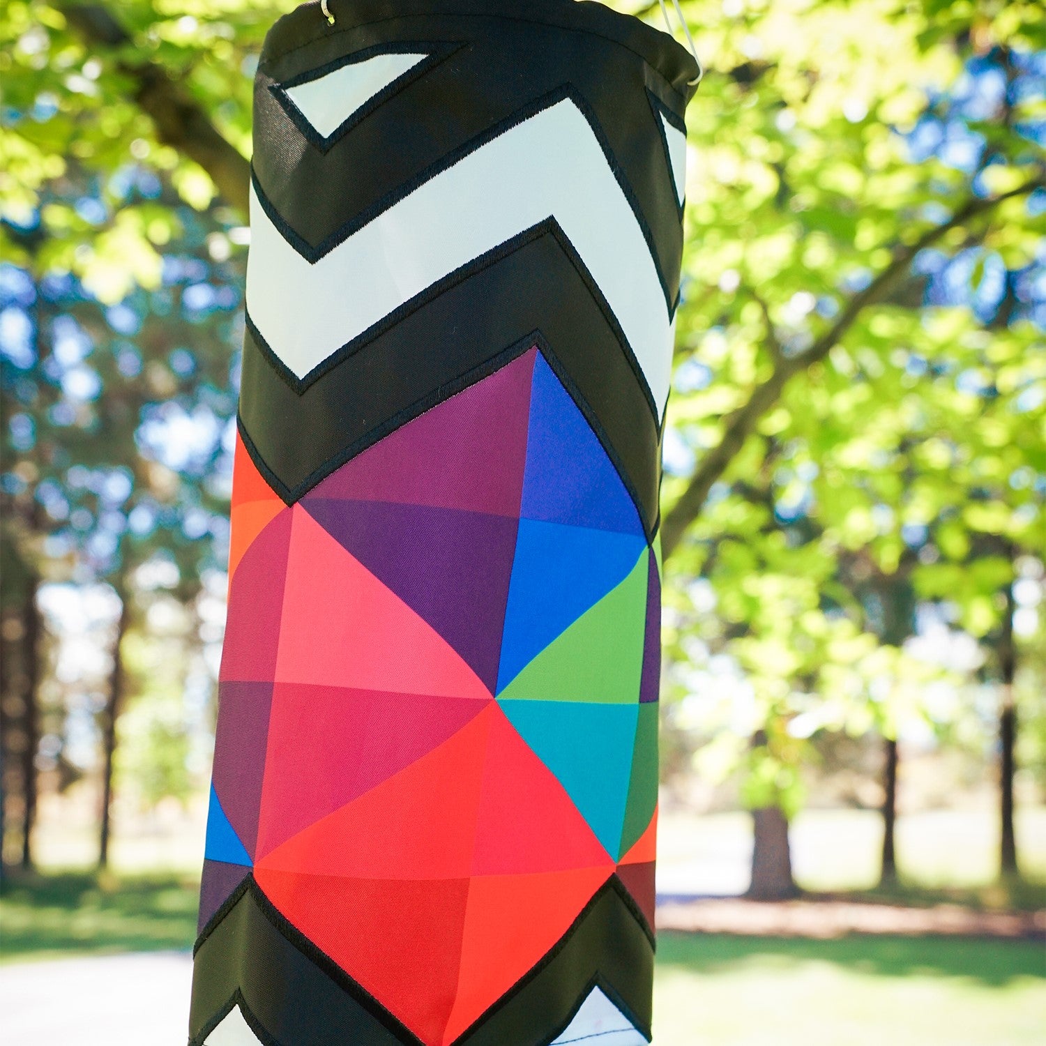 Geometric Black & White 40-inch Illusion Windsock hanging in a garden, featuring embroidered details and stunning printed tails creating a mesmerizing effect.