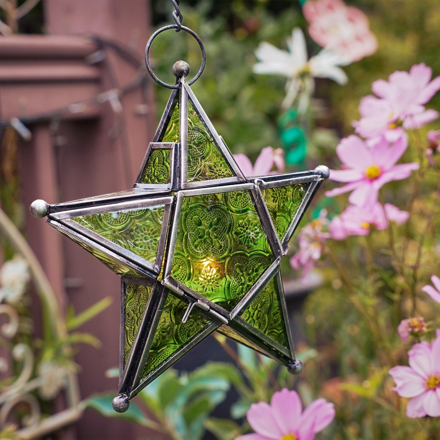 Green 5-Point Star Hanging Tealight Lantern, showcasing textured glass panels and a metal frame, suspended outdoors illuminating the night.