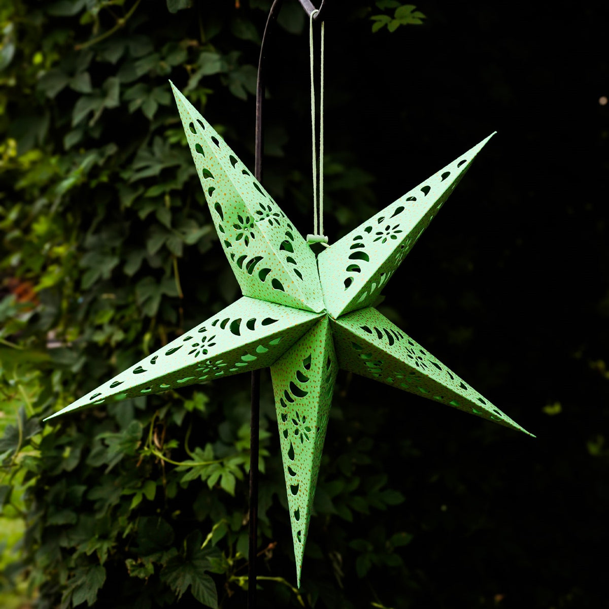 Green Paper Star Lantern with intricate cutouts and gold accents hanging indoors, designed for soft, ambient lighting and decorative appeal.