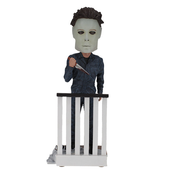 Halloween Michael Myers Glow in the Dark Mask Bobblehead leaning over a ghost-sheet prop with Bob's glasses, capturing slasher theme decor.