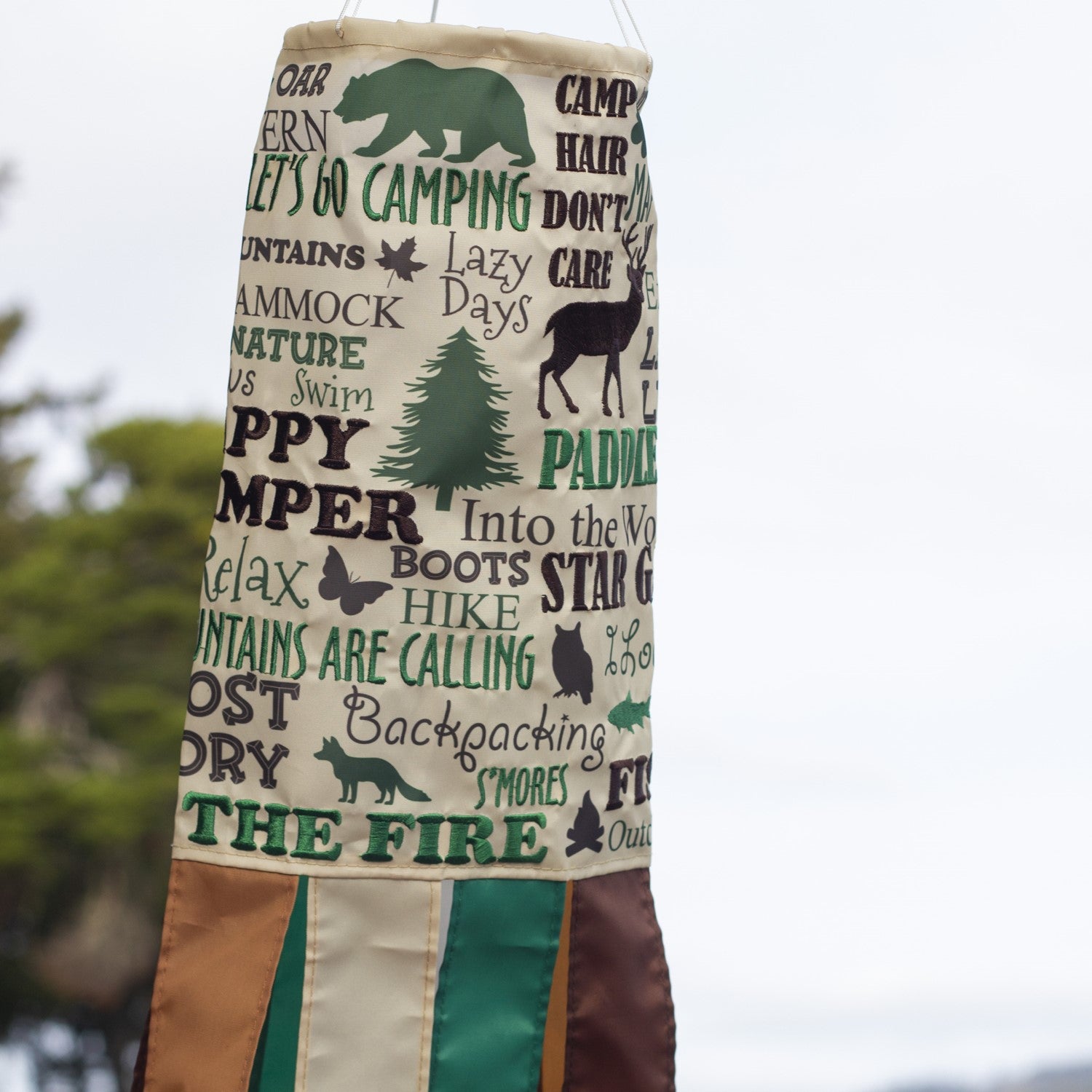 Happy Camper windsock featuring vibrant colors and detailed graphics, perfect for hanging outdoors in a garden or campsite setting to celebrate camping adventures.