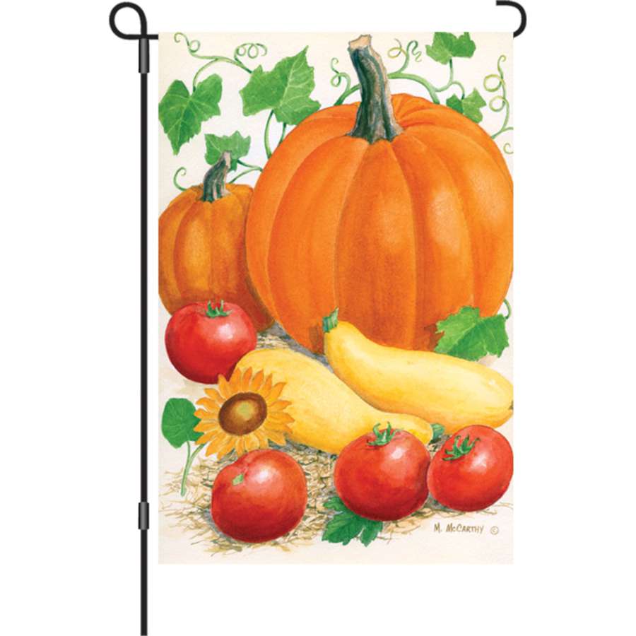 12 in. Harvest Time garden flag featuring autumn themes and bright colors displayed in a garden setting, illuminated for seasonal charm.