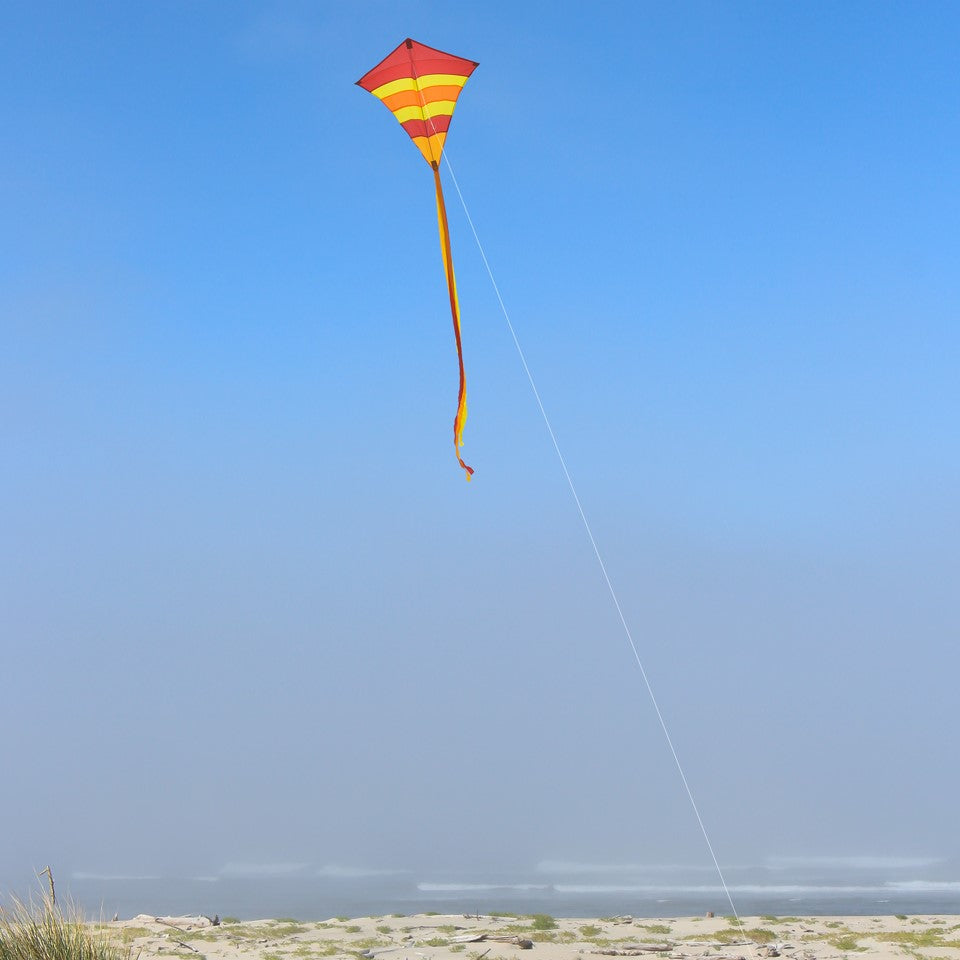 Hot Arch 27\" Diamond Kite with vibrant colors and 19-foot tails soaring in a clear blue sky, perfect for family outdoor activities.