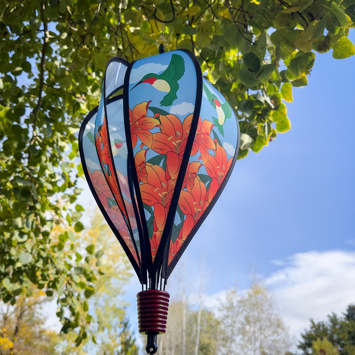 Hummingbird Lily Hot Air Balloon garden decor, showcasing vivid imagery of hummingbirds and lily flowers, spinning gently in the breeze.