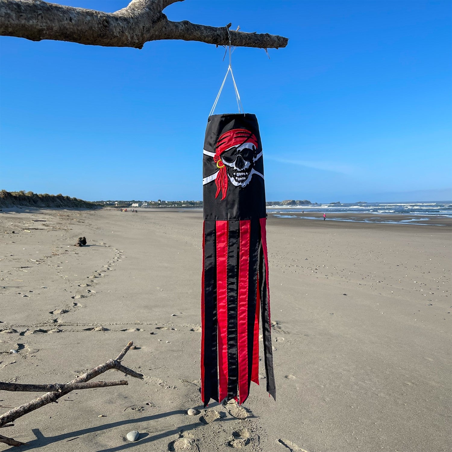 I'm a Jolly Roger 40" Windsock featuring a detailed pirate design with headscarf and gold earring, fluttering with vibrant tails in an outdoor setting.