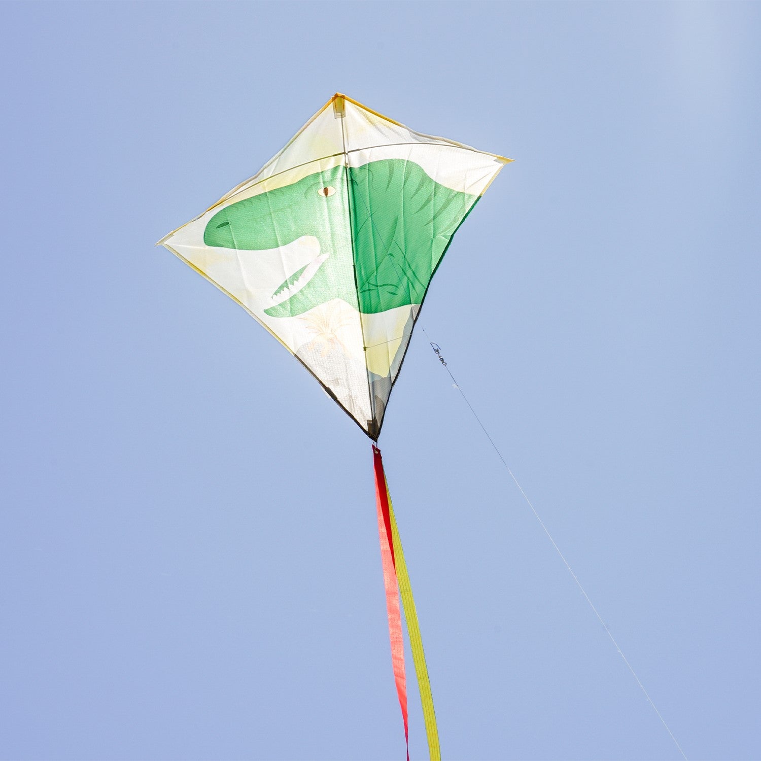 Alt Text: "Dinosaur 30-inch diamond kite with vibrant design and tails, flying in a clear blue sky on a sunny day, ready for outdoor fun.