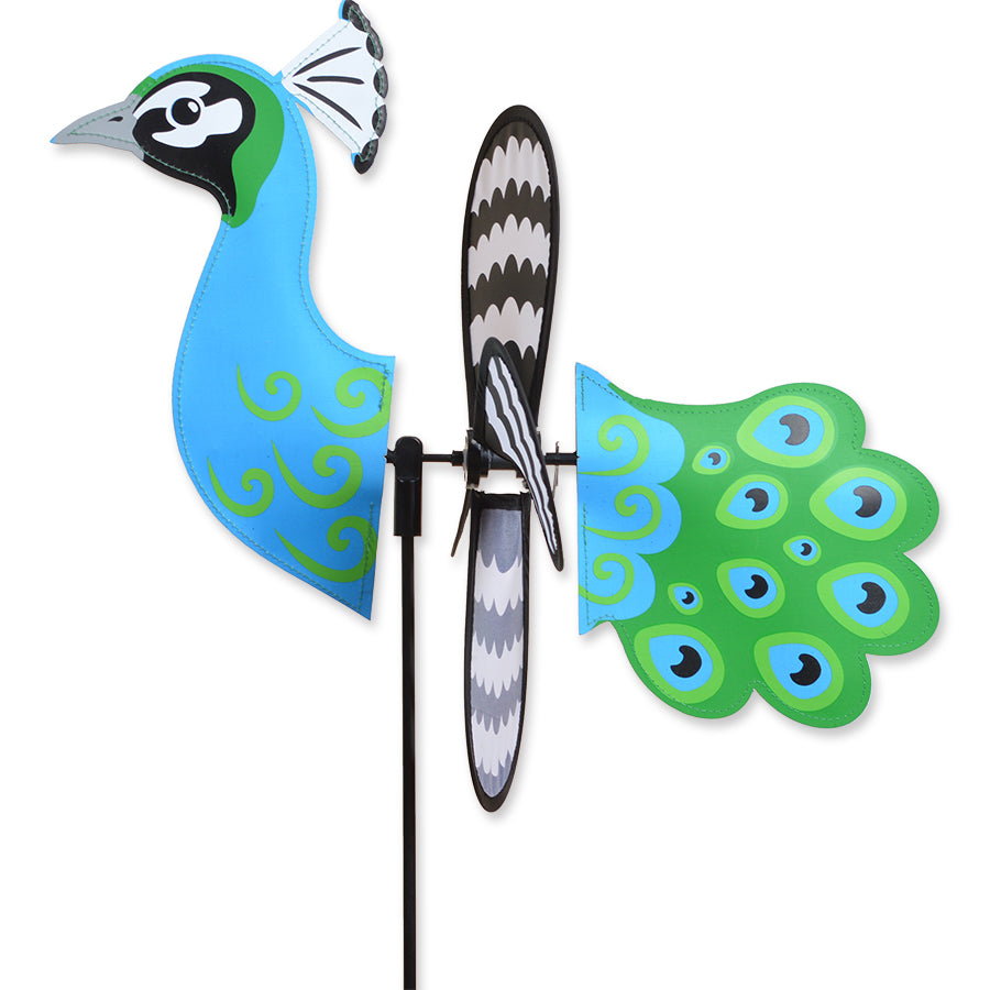 Alt Text: "Petite Spinner - Peacock in a vibrant design spinning outdoors in a garden setting, showcasing its colorful wings and adaptable display features.
