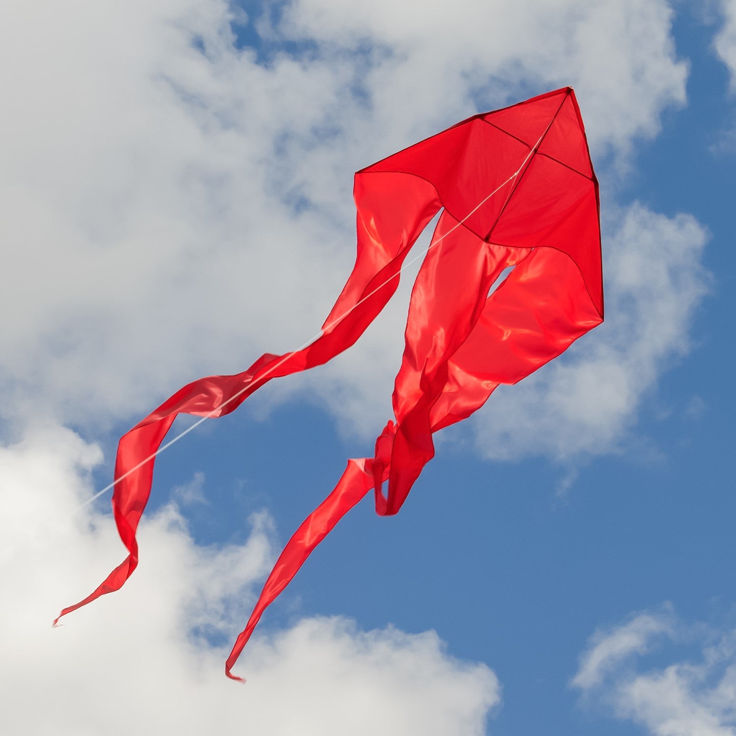 Alt Text: "Red 52-inch Wave Delta Kite soaring in a bright blue sky with long flowing tails, showcasing an elegant design perfect for outdoor fun.