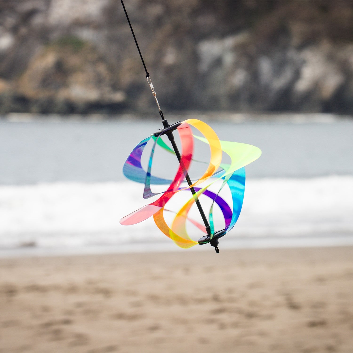 Iridescent Rainbow Vortex Spinner featuring six Mylar spirals hanging in a garden, shimmering in the breeze and reflecting light.