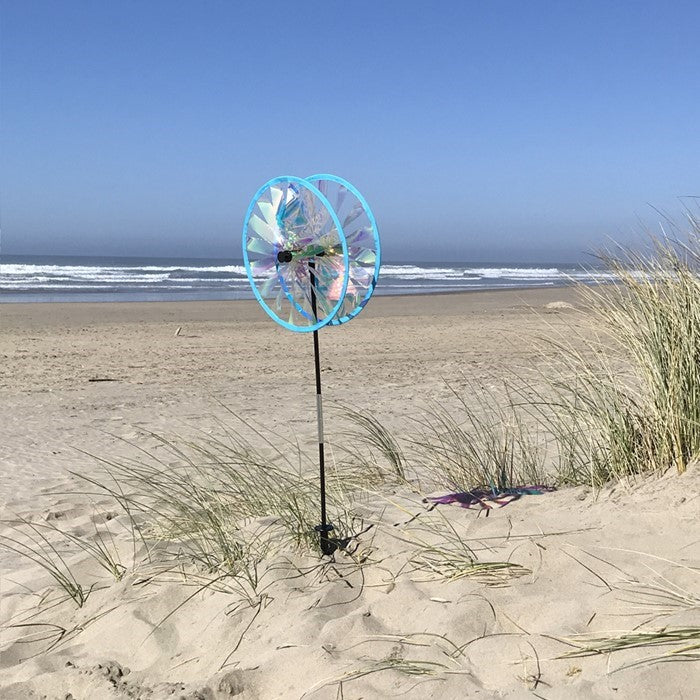 Iridescent Sparkle Duo Wheel Spinner with two colorful reflective wheels rotating in a vibrant outdoor garden setting.